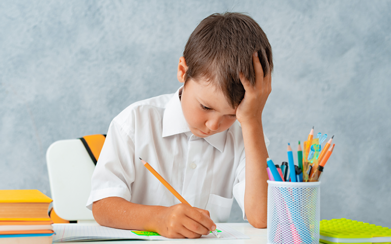 A schoolboy solves his homework at a desk