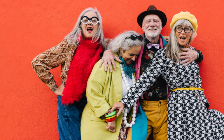 Group of cheerful elderly friends celebrating their retirement in colourful clothing.