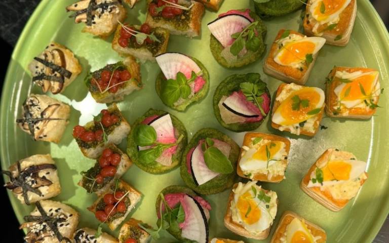 A variety of canapes displayed on a green plate.