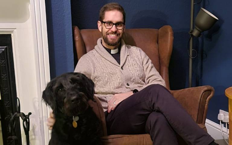 Reverend Reid pictured sitting in a chair with his dog, Magnus 