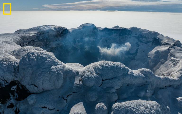 The crater at the peak of a snowy volcano