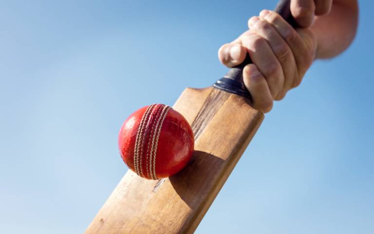 A cricket ball being hit by a cricket bat