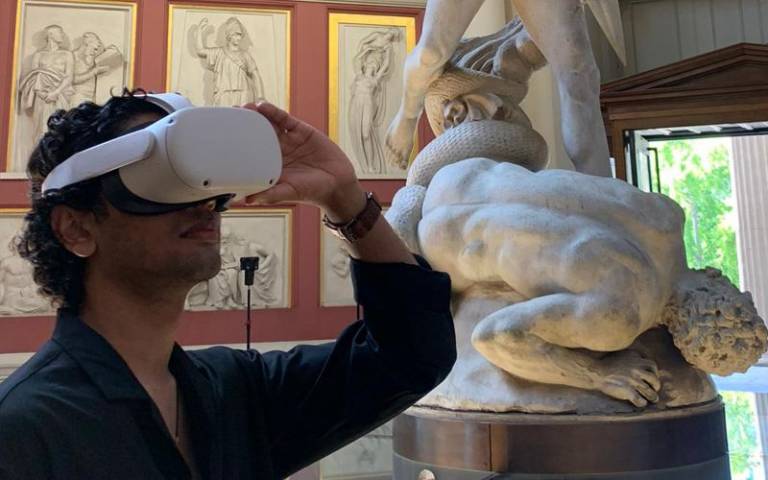 Man wearing a VR headset in a museum with sculptures behind him