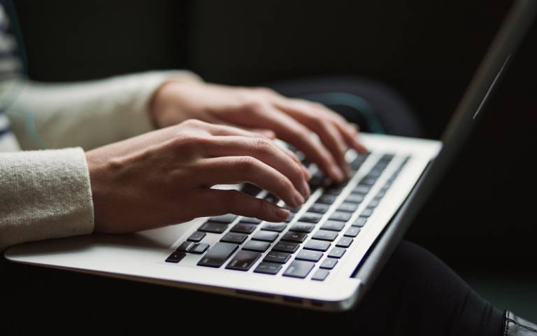 A hand is typing on a Macbook laptop