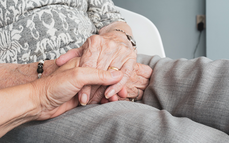 An image of a women holding an older woman's hand