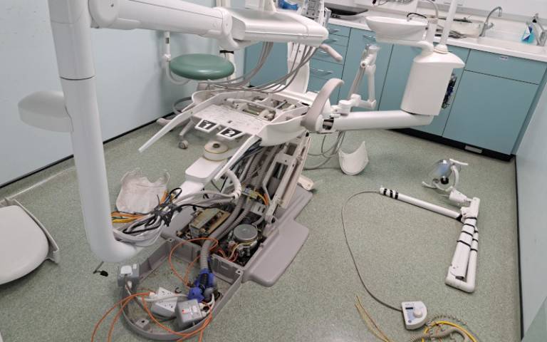 A partially-dismantled dentist chair with the seat removed and internal mechanisms visible