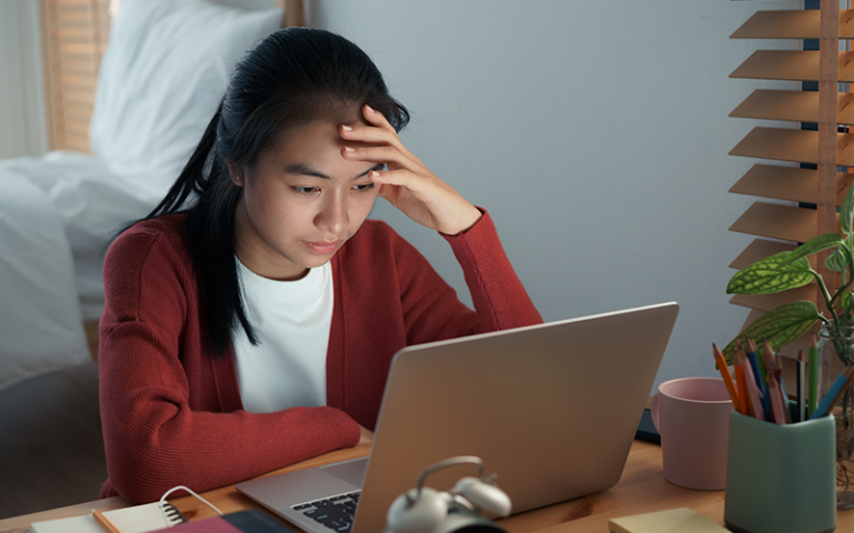 Girl are sitting stressed studying online with a tutor on a laptop while sitting in the bedroom at home night. Concept online learning at home