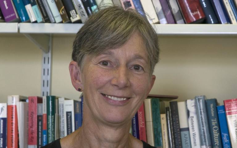 Professor Catherine Hall smiling with a bookcase behind