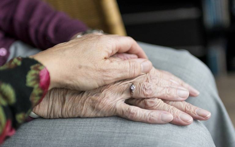 a younger pair of hands on top of a more elderly pair of hands