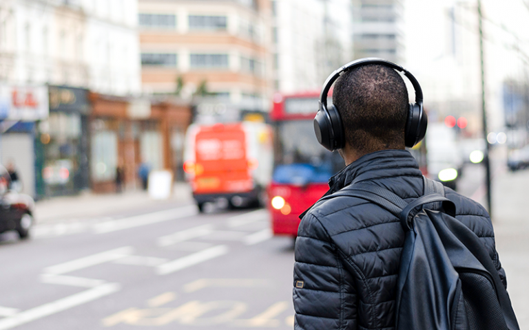 A person listening using their headphones while standing in a street
