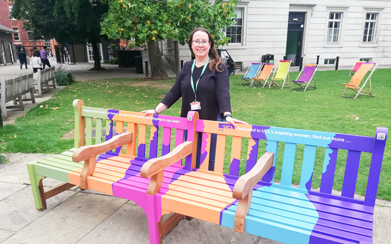 A person standing beside a multicoloured bench on UCL's campus