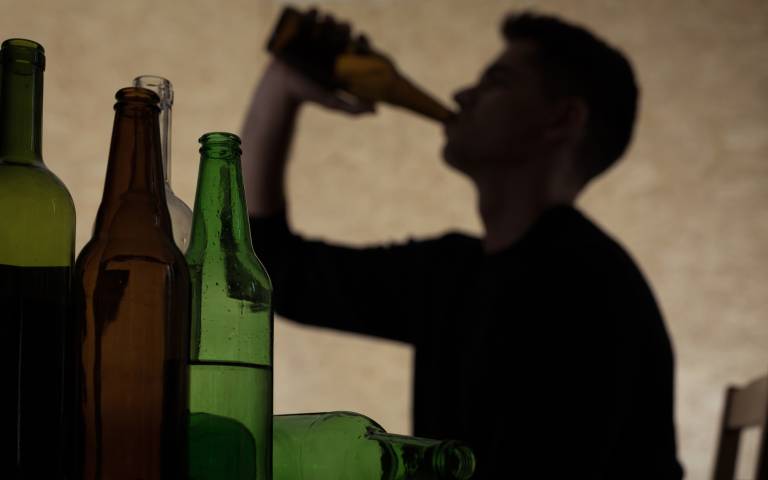 Silhouette of teenage boy drinking from a bottle with bottles in the foreground