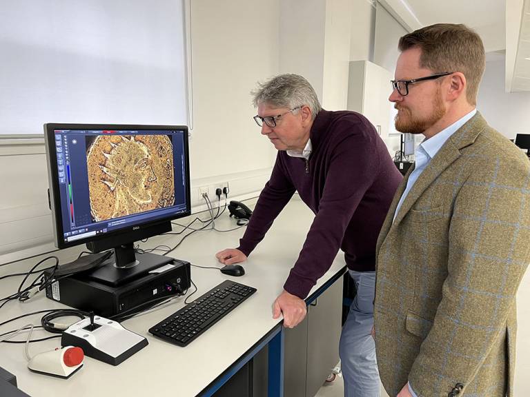 Professor Paul N. Pearson and Jesper Ericsson, The Hunterian, University of Glasgow, look at the Sponsian coin under a microscope.