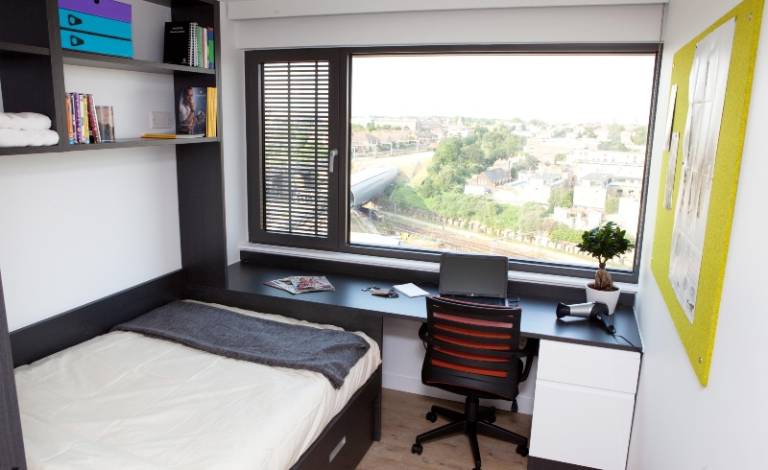 An en-suite student room featuring a bed, a desk, a chair and a big window