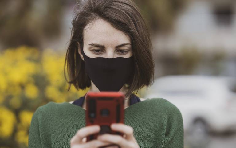 woman in mask holding phone