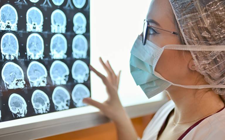 a person in surgical clothing looks at an MRI scan