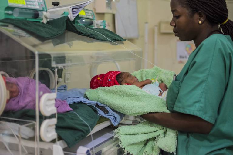 healthcare worker holding a baby at a hospital. Photo courtesy of GARDP