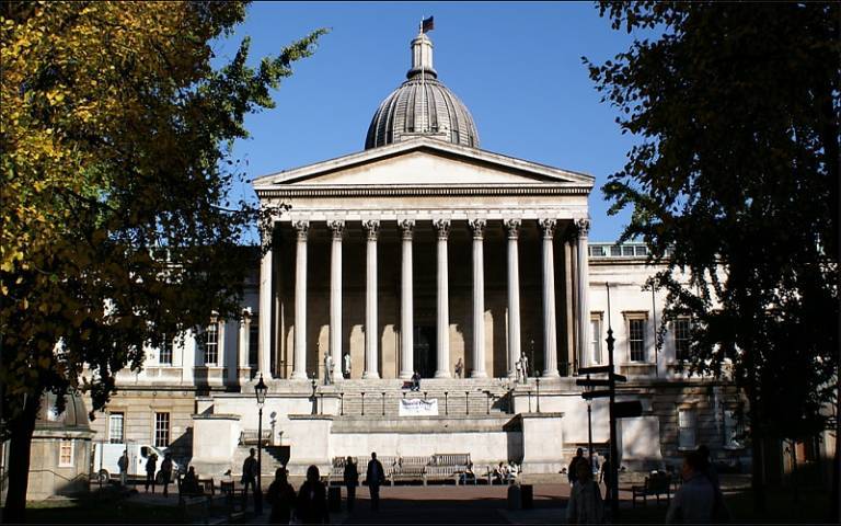 UCL's Portico building under a blue sky, seen from a shadier part of the Quad