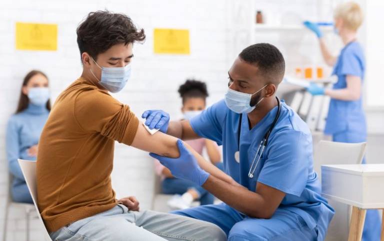 Asian Male Patient Getting Vaccinated Against Coronavirus Receiving Covid Vaccine Intramuscular Injection During Doctor's Appointment In Hospital