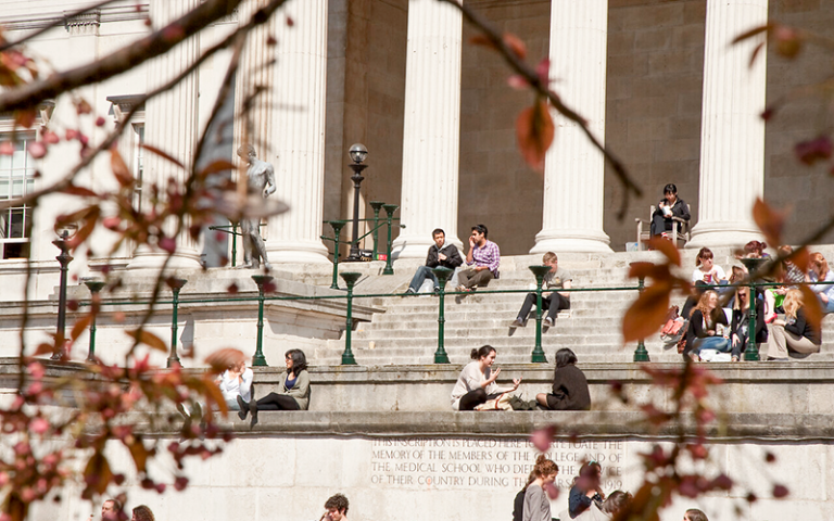 Students sitting on the steps on the UCL quad building on a sunny day