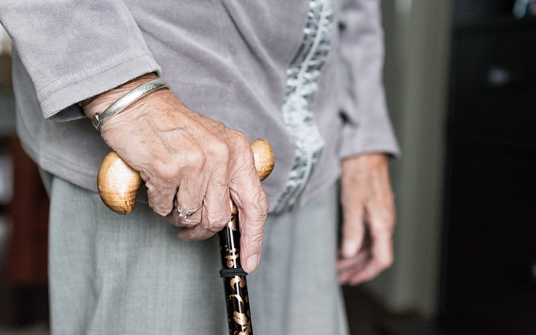 an image of an elderly women holding a walking stick. 