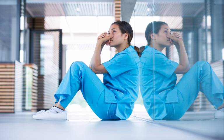 worried nurse sitting on floor of hospital stock photo