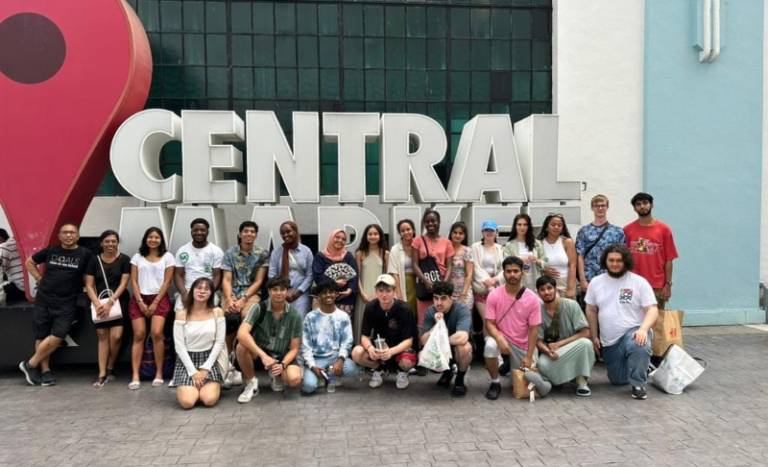 A group of people smiling in front of a big signage saying 'central'