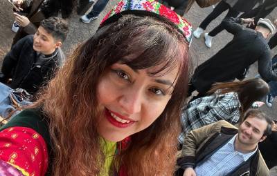 A selfie of Arifa in front of the quad. She is wearing a hat at an event of Nawroz.