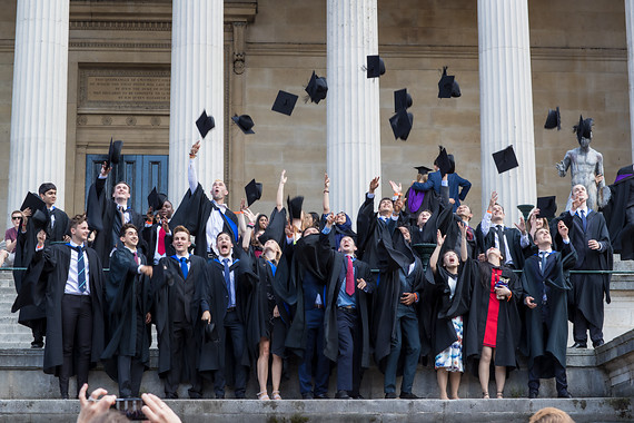 Graduates throwing mortarboards in the air in front of the Portico