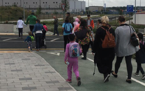 A group of people and children walking on a paved path 