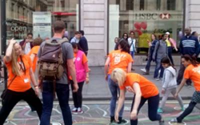 A group of people in a London street wearing orange colours, doing an activity