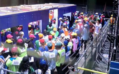 A large group of people with hard hats crowd around a tube train model