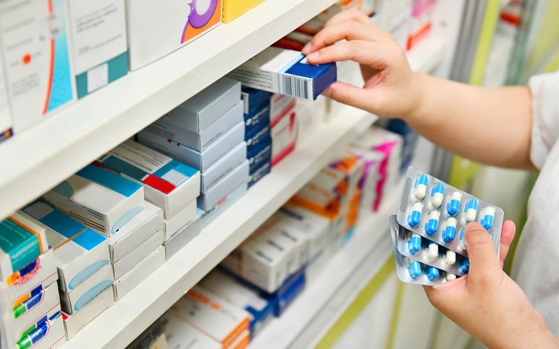 Pharmacist taking tablets from shelves