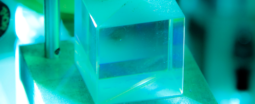 Close up of clear cube on experiment apparatus in blue-green light 