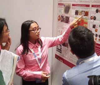 Princess Buma-At pointing towards her research poster while explaining her work to two other attendeees