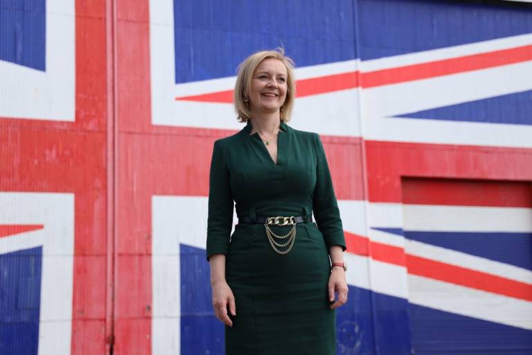 Liz Truss standing in front of British flag