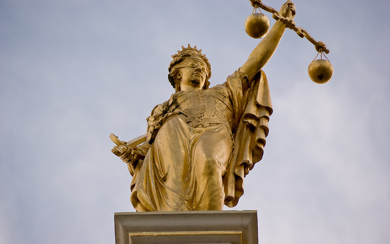 A golden statue of Lady Justice is seen from below