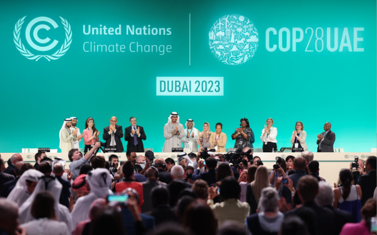 COP28 leaders stand in front of a crowd who are clapping