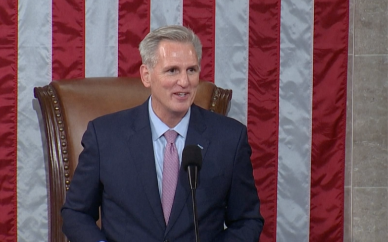 Kevin McCarthy gives a speech after winning the Speaker elections. He is smiling in front of the USA flag