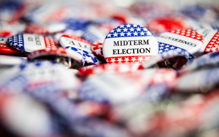 A pile of badges with the USA flag and the words 'midterm election' on them.
