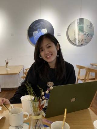 Ziqian is working in a cafe, smiling at the camera