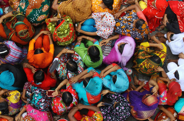 group of women sitting on the floor in colourful saris 