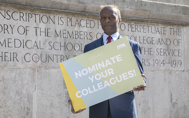 A UCL staff member holding a sign saying 