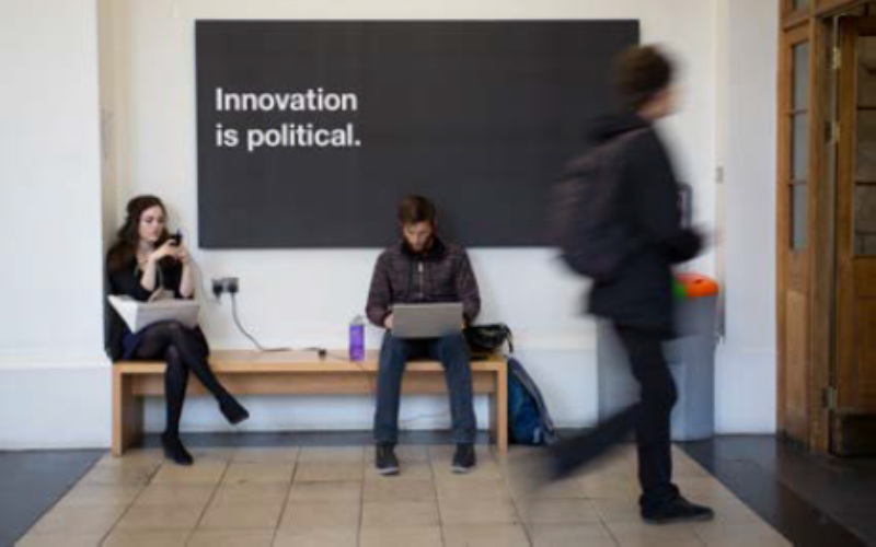 Students site under a sign that says "innovation is political"
