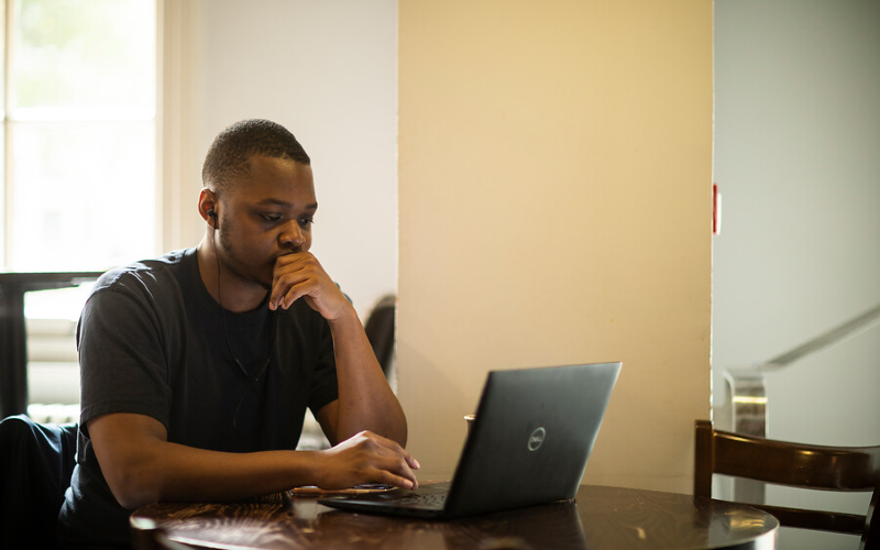 A student looks at a laptop on a desk.