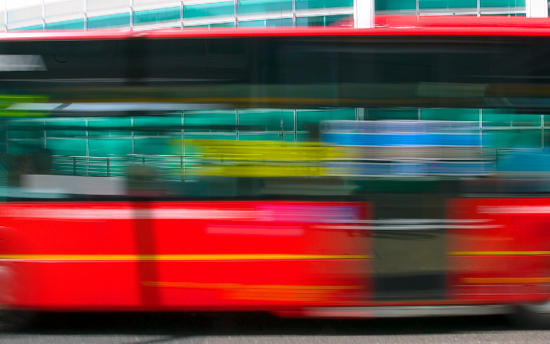 A blurred image of a red London bus passing.
