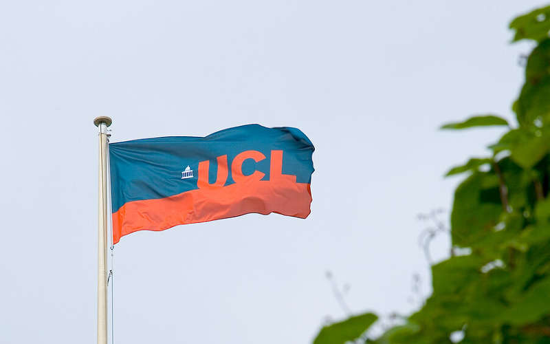 A blue and orange UCL flag high up on a flag pole.