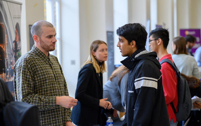 A student speaks to a member of staff on UCL campus.