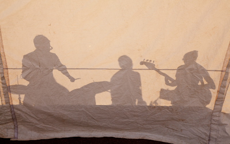Silhouette of musicians against tent. 