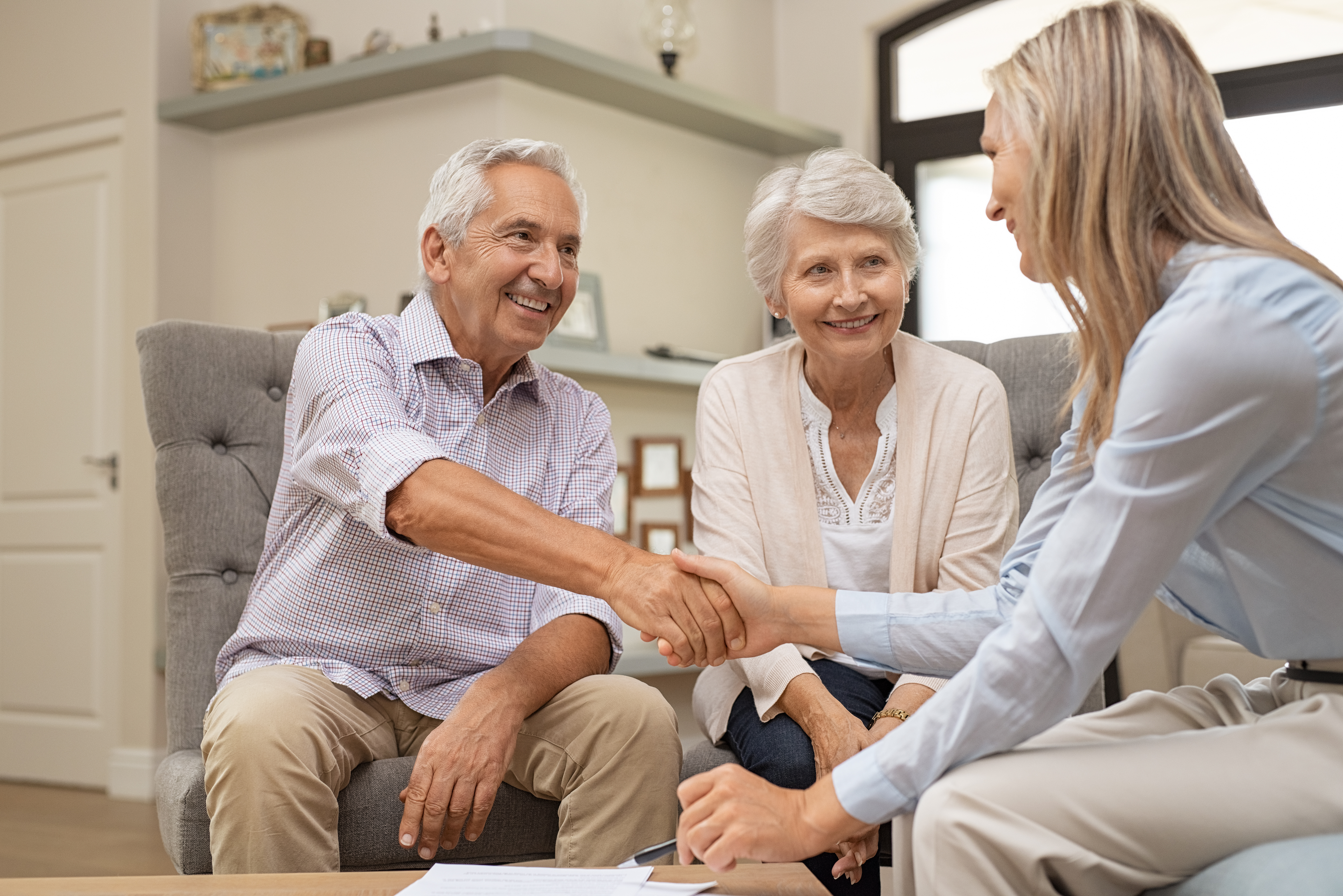 elderly couple shaking hands with woman